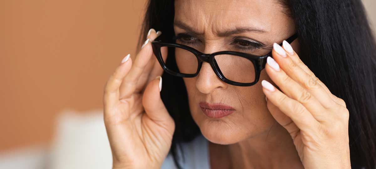 Une femme mûre cligne des yeux, essaie de regarder de plus près à travers des lunettes